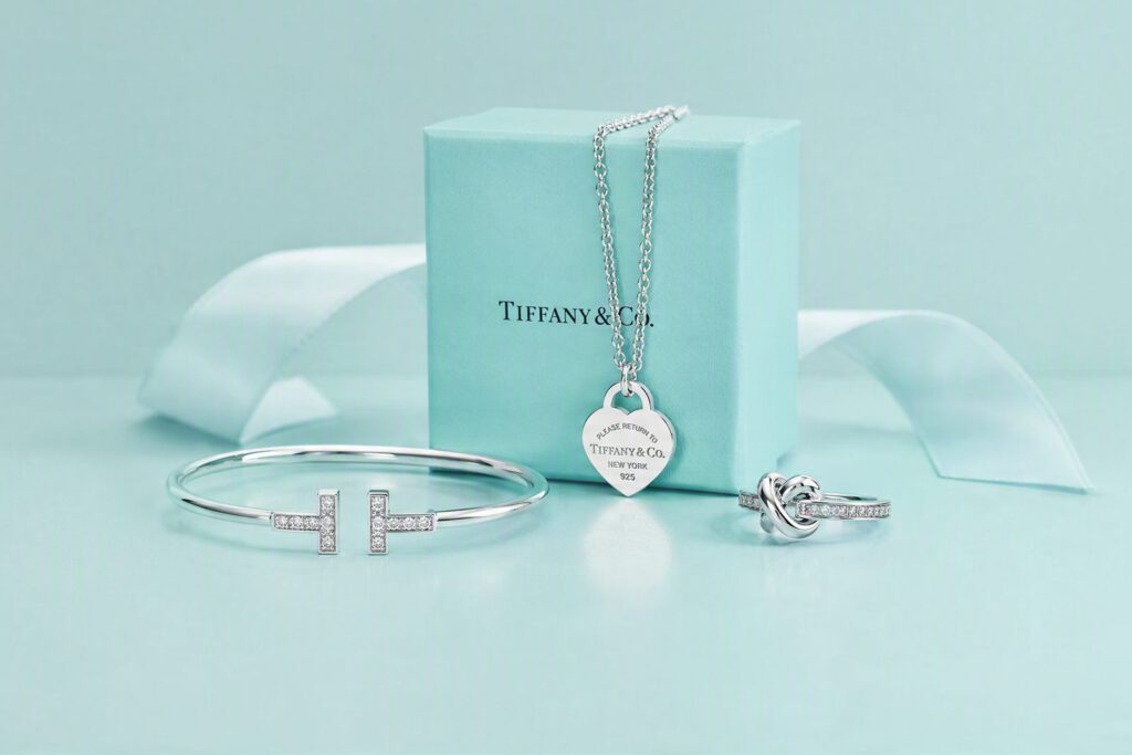 Tiffany-Schmuck vor der türkisfarbenen Schachtel: Anhänger, T-Armreif und Knotenring